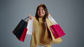 Fun cute shopaholic woman hold many shopping bags gray isolated studio background. Joy girl buy trendy clothing. Person wear yellow t-shirt. Lot colorful packages. Ad mock up. Low price sale addiction - Powered by Shutterstock - Get 15% off with code: PIKWIZARD15