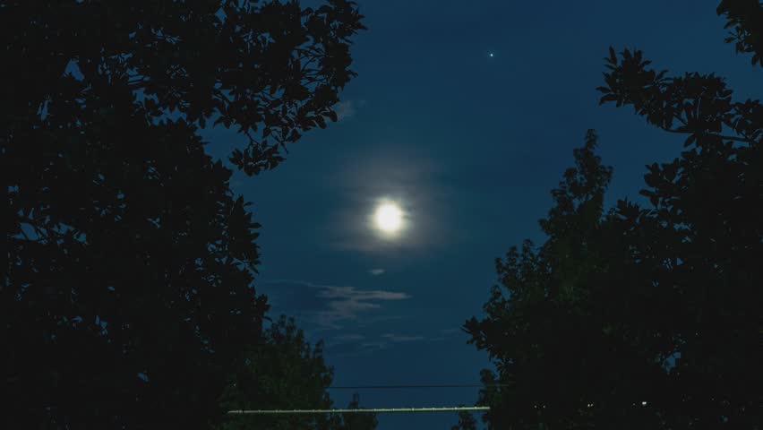 Clouds are passing in front of the moon on a summer night