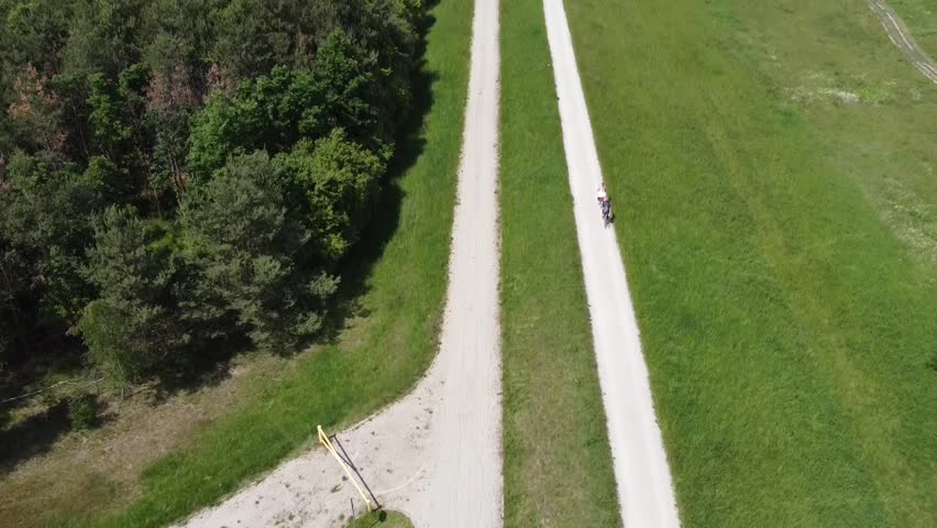A drone shot of flood embankments and a bike path next to a river and green areas during summer