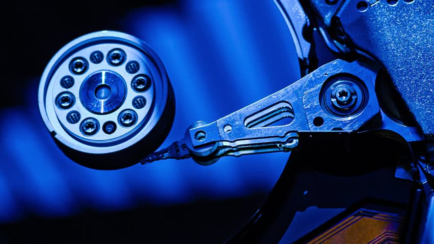 Hard drive read head moving over a spinning platter on a blue background