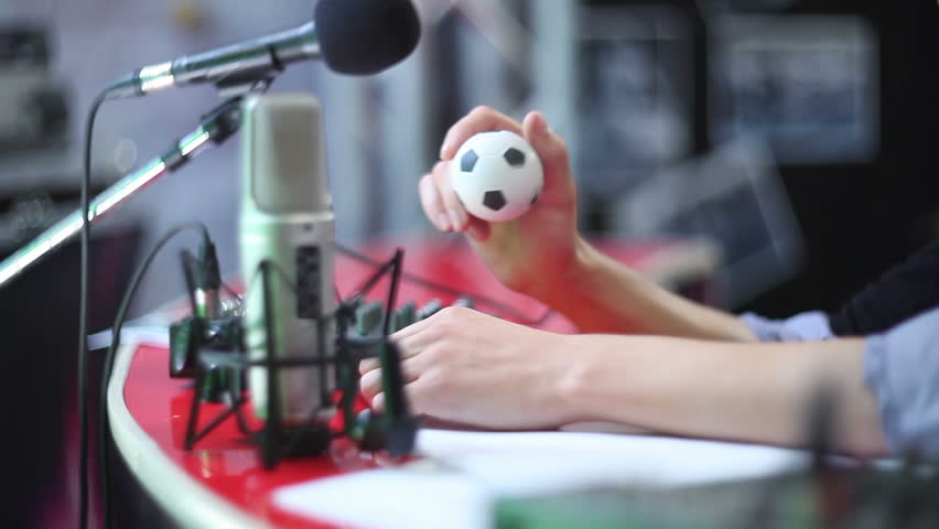 Man behind microphone taps toy ball and talks. Radio show dj on air