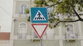 Traffic signs indicating a pedestrian crosswalk and a yield requirement, set against the backdrop of a green building and tree in an urban area. Closeup on road sign of pedestrian crossing on street - Powered by Shutterstock - Get 15% off with code: PIKWIZARD15