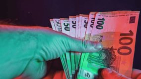 Person counts a stack of 100 and 50 euro banknotes under colorful lights - Powered by Shutterstock - Get 15% off with code: PIKWIZARD15
