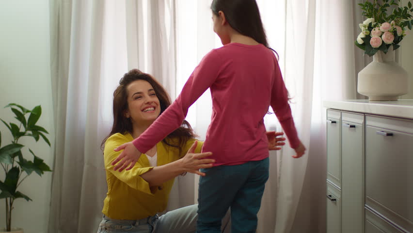Happy family bonding Caucasian woman female mom mother hug embracing cuddling little girl child kid returning from school lessons daughter hugging foster parent indoors home kitchen. Adoption custody