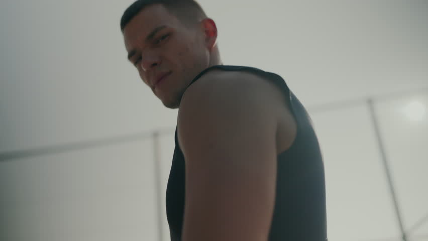 Determined young man in workout gear intensely focusing during a fitness session inside a brightly lit gym. The mood is serious and motivated. Young Man During an Intense Workout Session Indoors