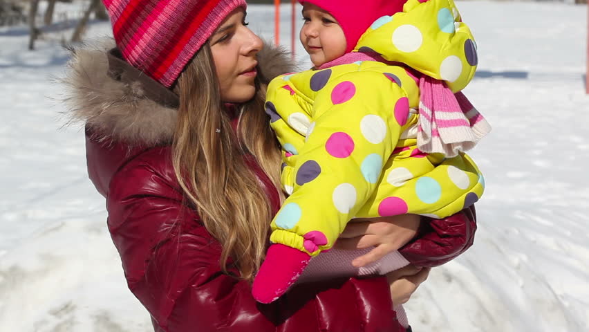 Pretty mother in winter clothes holding her daughter at winter