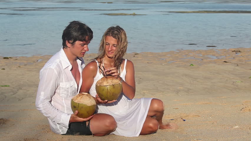 Attractive happy couple with coconuts have dating at tropical beach