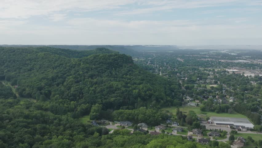 Aerial footage of famous Grandad Bluff surrounded with lush greenery. The 600-ft high bluff overlooks the city of La Crosse, the Mississippi River Valley, Wisconsin, Minnesota, and Iowa in USA.