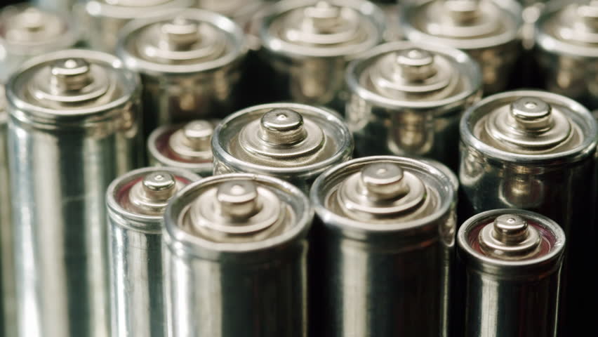 Silver batteries AA and AAA on black background close-up. Double-A battery is a standard size single cell cylindrical dry battery. Batteries are common in portable electronic devices. An AA battery is