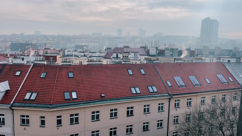 Skyline view of a city with rooftops and distant buildings under a cloudy atmosphere in Prague