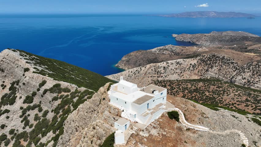 Aerial drone cinematic video with stunning view from uphill chapel of Prophet Elias of Troulaki overlooking port of Kamares, Sifnos island, Cyclades, Greece