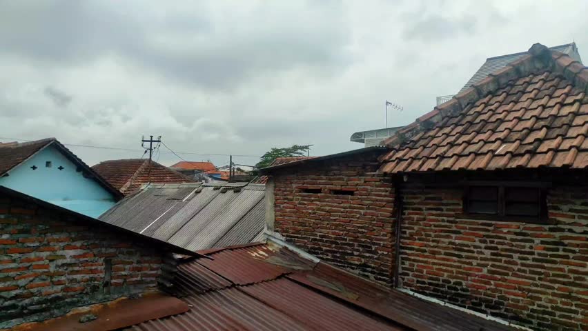Overcast weather above a densely populated neighborhood with modest housing, showcasing the urban life of low-income residents.