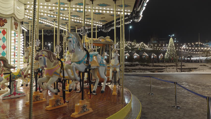 Illuminated Merry Go Round spinning.  Empty old fashion roundabout in park.