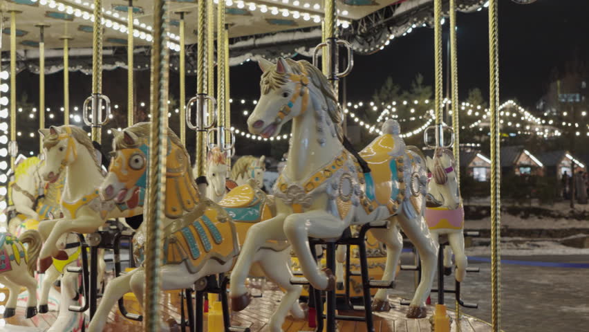 Illuminated Merry Go Round spinning.  Empty old fashion roundabout in park.