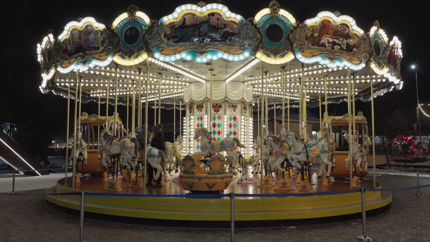 Illuminated Merry Go Round spinning.  Empty old fashion roundabout in park.