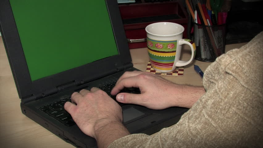 A man uses a laptop.  Green screen.  With alpha matte.