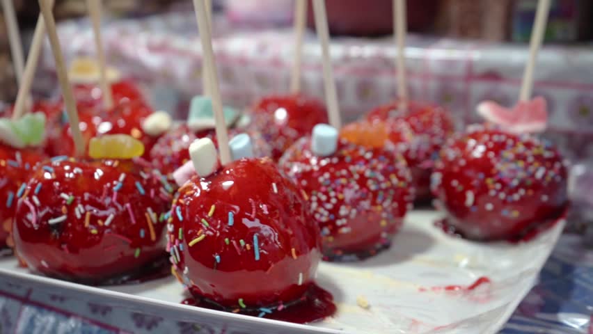 Apples covered with a shiny caramel glaze, carefully placed on a tray, ready to be served and enjoyed as a delicious dessert.