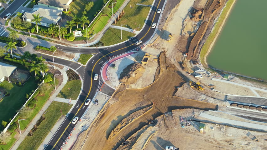 Industrial construction roadworks at roundabout intersection with moving cars in Venice, Florida. Development of urban circular transportation crossroads.