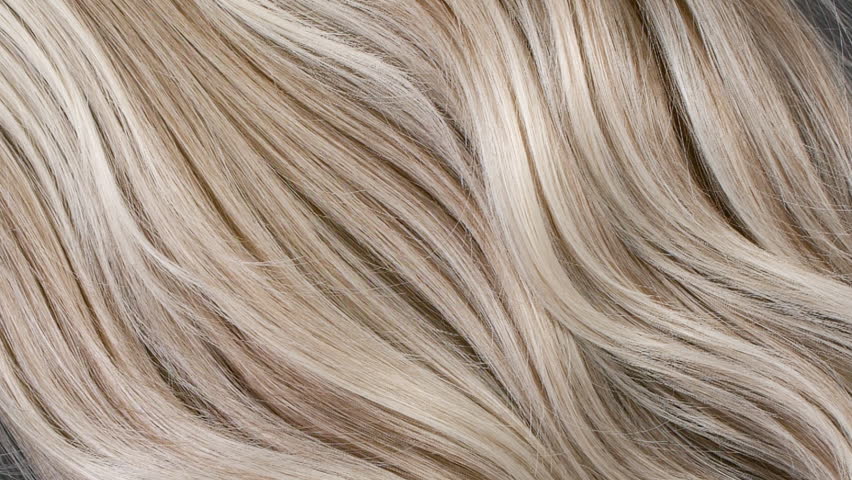 Close-up blond hair texture, slow motion of female hand combing long curly hair