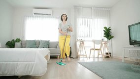 Smiling housekeeper with headphone listen music while cleaning floor. Happy caucasian mother mopping floor while dancing to lively song at living room. smiling mom doing housework. Lifestyle. Pedagogy - Powered by Shutterstock - Get 15% off with code: PIKWIZARD15
