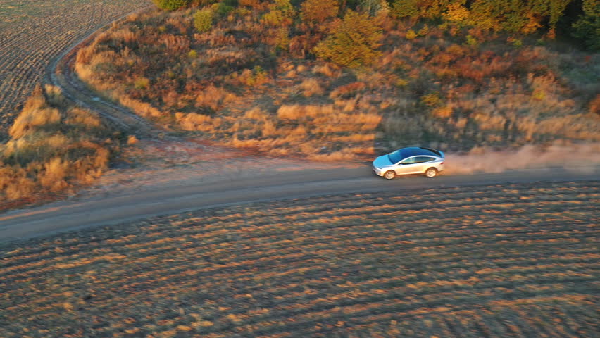 Aerial view of electrical car speeding through dusty route. Ecology friendly auto on electric charge driving along rural road. Concept of freedom or modern technologies.