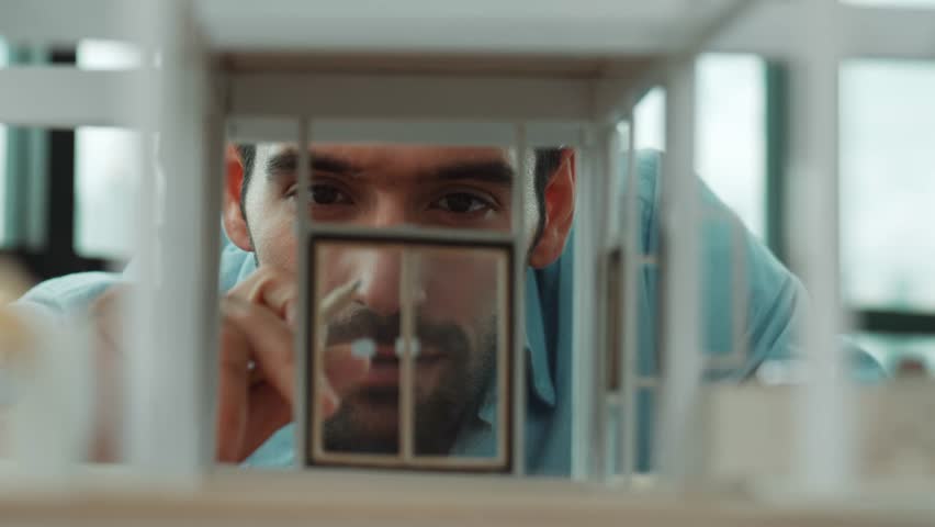 Closeup of young caucasian skilled architect engineer focusing on checking the house model structure with confident. Male worker looking at house construction. Creative design concept. Tracery