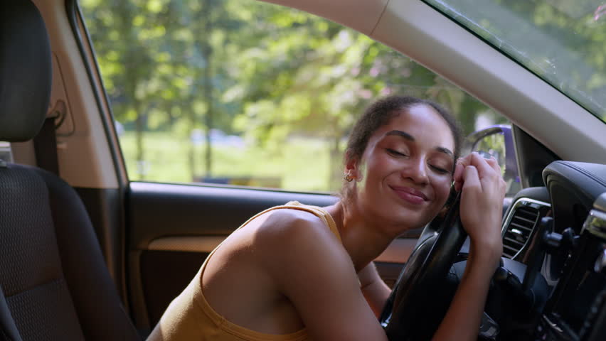 Happy African American woman buyer female sit luxury new car auto hugging wheel steering owner automobile buying enjoy businesswoman vehicle embrace hug rent service test drive cuddling girl business