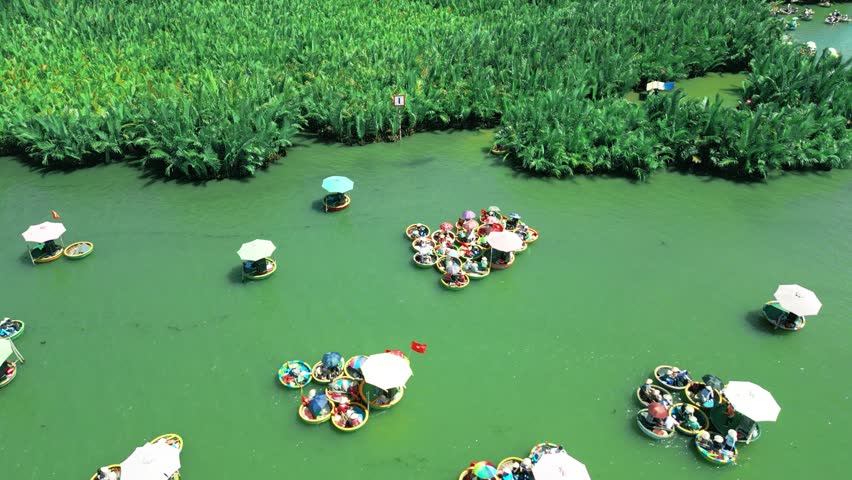 Vibrant round boats navigate the lush riverside surrounded by palm trees, showcasing the charm of Hoi An, Vietnam.