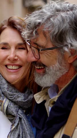 Vertical HD video: Portrait of senior adult attractive couple laughing together at city street. Retired people bonding outdoors.