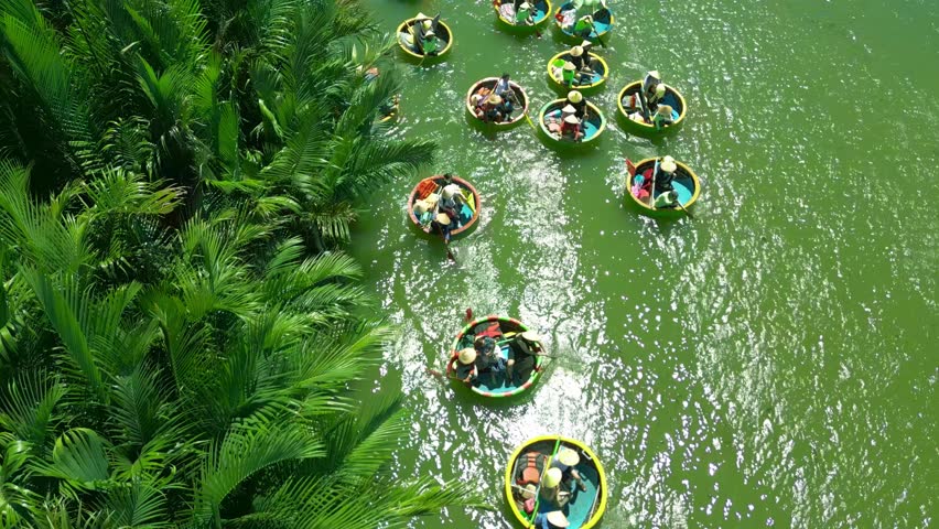 Colorful round boats float through a lush river, surrounded by palm trees, showcasing the scenic beauty of Hoi An, Vietnam.
