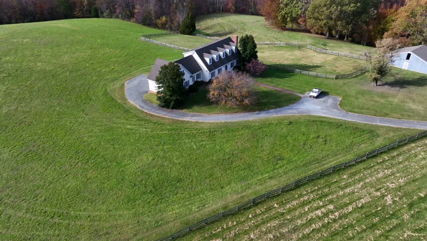 Large farm housing rural area of Virginia. Large property with garden and colorful forest in background. Aerial tilt up wide shot. Sunny day in fall.