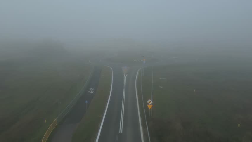 Foggy aerial view of an empty rural roundabout on a misty morning with low visibility