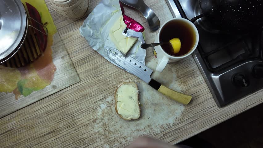 A man spreads butter on bread. White bread and butter.