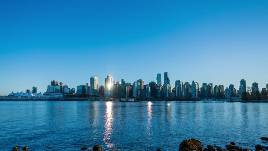 Vancouver downtown city skyline. Colorful buildings lights reflected in water. Time-lapse sunset to night. British Columbia, Canada.