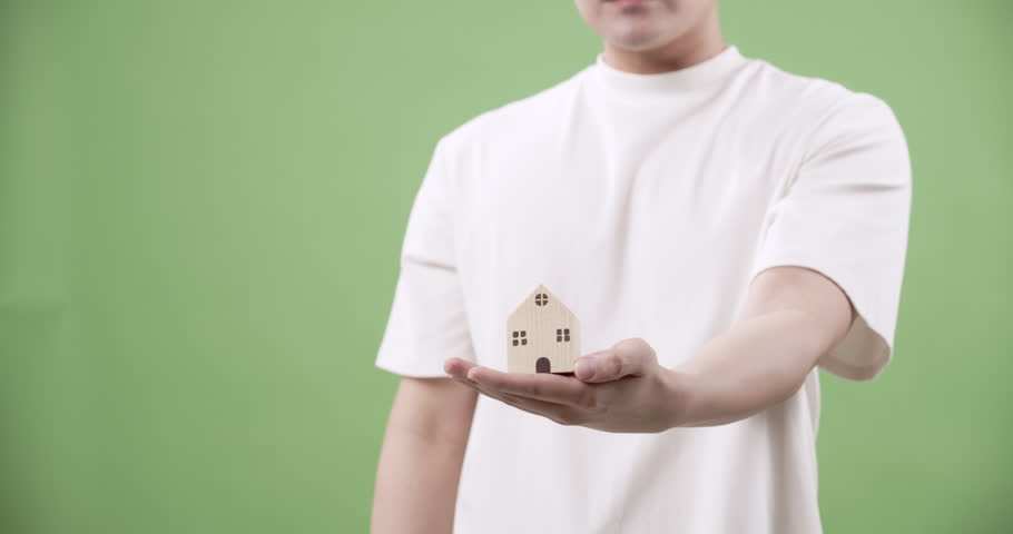 A man demonstrates the importance of home protection by shielding a miniature house symbolizing security and safety for homeowners.