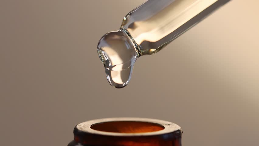 Pipette with brown cosmetic bottle close-up. A drop of hyaluronic acid falls into the bottle.