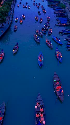 Vibrant boat rides illuminate the Bon River, surrounded by lanterns, capturing the enchanting atmosphere of Hoi An old city at dusk.