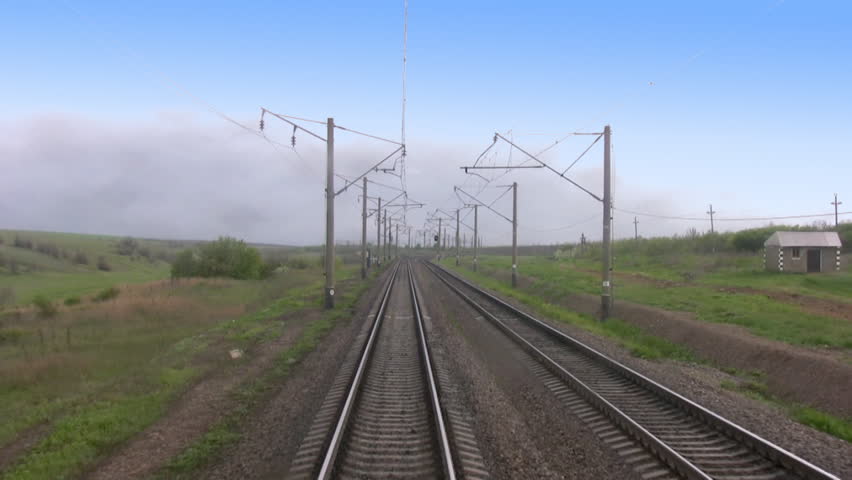 View from the last car of a train. Rails run away. Train departs from the clouds