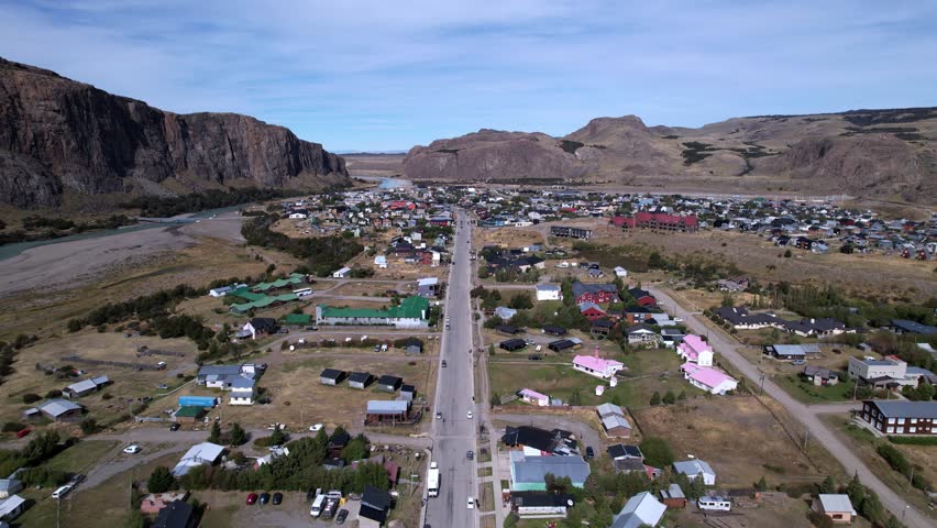 Aerial Drone Footage Captures El Chaltén Village In Argentina, Showcasing Small Houses Nestled Among Majestic Mountains. The Cold, Cloudy Summer Day Enhances The Serene Atmosphere.