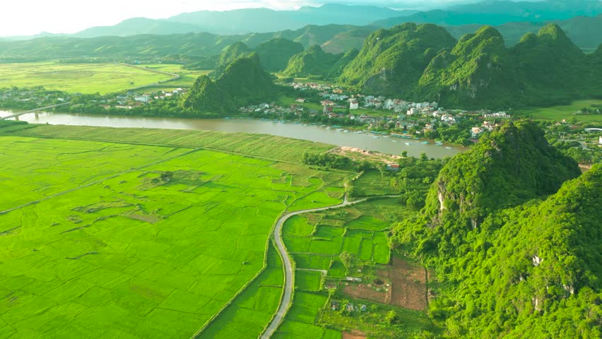 A stunning aerial view showcases lush tropical mountains surrounding a winding river, revealing the beauty of Phong Nha in Ke Bang National Park, Vietnam.