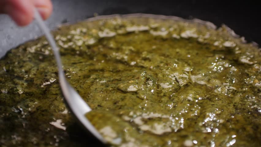 Cooking green pesto sauce close-up. Italian Pesto is a sauce that traditionally consists of crushed garlic, European pine nuts, coarse salt, basil leaves, and hard cheese such as Parmigiano-Reggiano