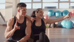 Athletic couple Generation Z in sportswear in training sit and using modern smartphone in fitness room in sunny day, woman and a man take pictures of themselves in the gym, Side view 4K B-Roll footage - Powered by Shutterstock - Get 15% off with code: PIKWIZARD15