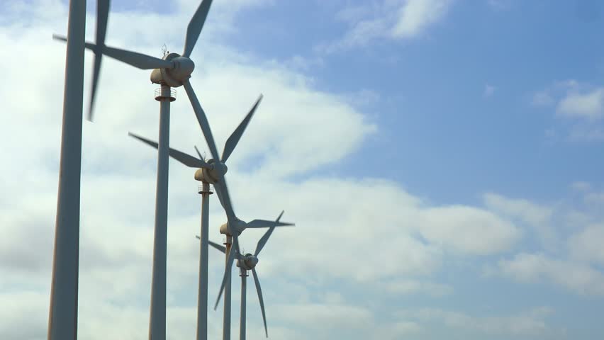 Tall wind turbines generating power in the countryside, focus on renewable resources under cloudy sky with open space for text