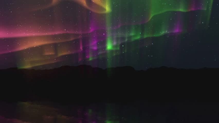 Majestic Northern Lights Dance Above Silhouetted Mountains.