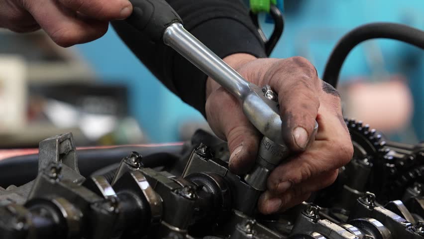 Mechanic repairing a car engine with a handheld wrench tool, demonstrating expertise and precision, detailed closeup