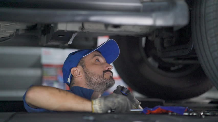 Worker in uniform, car service. Automobile technician. Mechanics in uniform are examining car while working in auto service.
