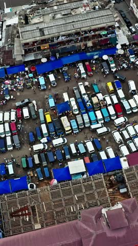 A lively market scene in Accra, Ghana, with a vibrant assortment of parked vehicles and bustling vendor stalls under colorful tarps, showcasing daily life.
