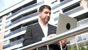 Mature adult caucasian businessman checking time to smartwatch while standing using laptop at city - Powered by Shutterstock - Get 15% off with code: PIKWIZARD15