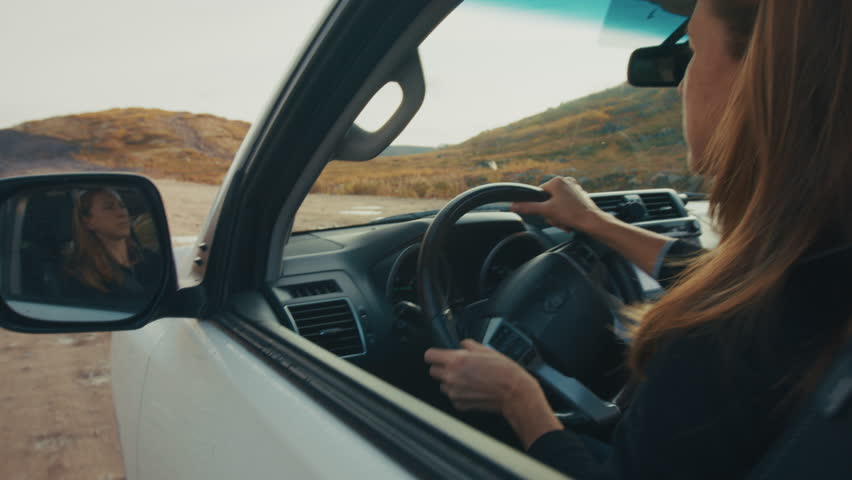 Young woman steers the big 4x4 car on a bumpy unpaved road