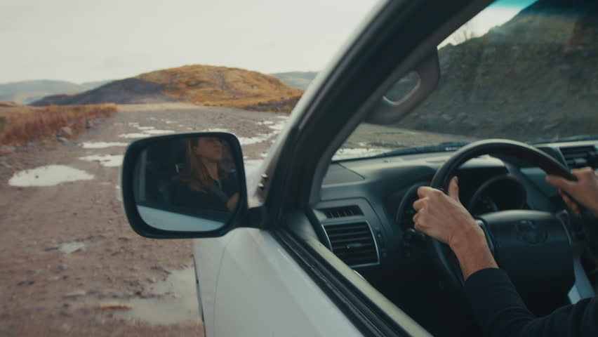 Young woman steers the big 4x4 car on a wet and bumpy unpaved road